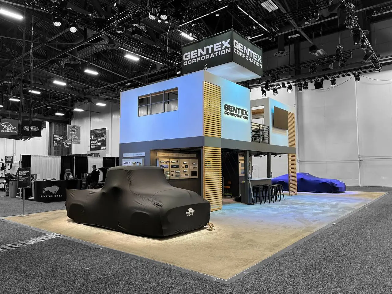 Gentex two-story booth with covered vehicle at SEMA 2025